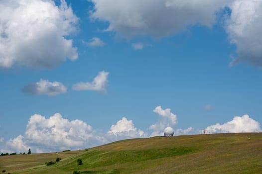 Radome (antenna dome) on the Wasserkuppe with a green meadow and blue sky and copy space