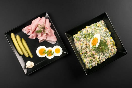 Luxury gourmet appetizer with Russian salad, ham, eggs and pickle on black background.