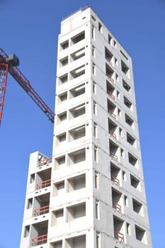 A high-rise building is being built. For fire protection,the stairwell of the office building was made of concrete. The construction crane transports the building materials to the upper floors.