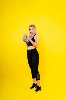 Perfect sporty female working out with dumbbells. Photo of woman in sportswear, studio shot