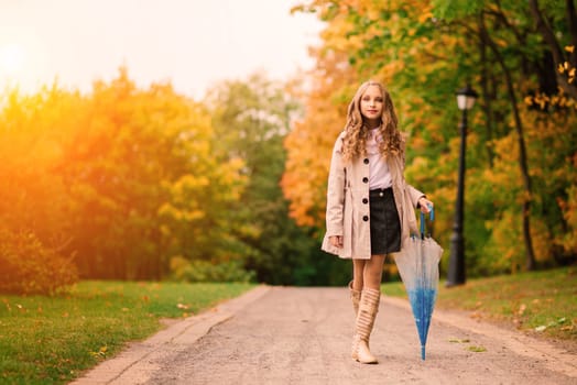 Young attractive smiling girl under umbrella in an autumn forest