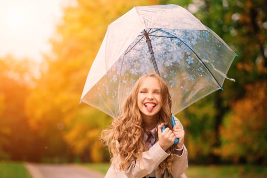 Young attractive smiling girl under umbrella in an autumn forest
