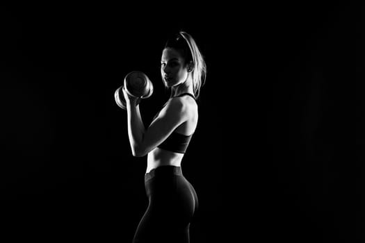 Perfect sporty female working out with dumbbells. Photo of woman in sportswear, studio shot