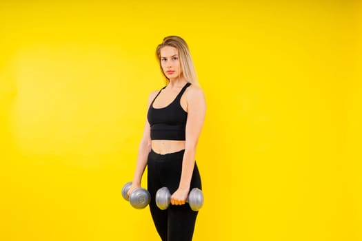 Perfect sporty female working out with dumbbells. Photo of woman in sportswear, studio shot