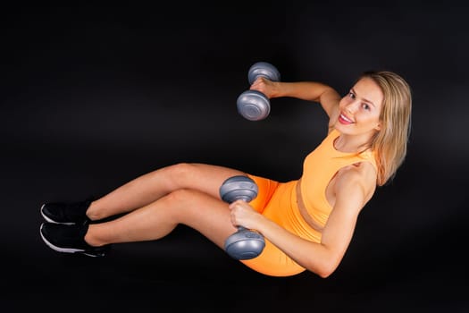 Perfect sporty female working out with dumbbells. Photo of woman in sportswear, studio shot