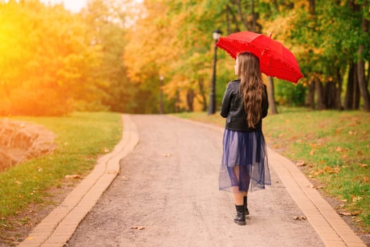 Young attractive smiling girl under umbrella in an autumn forest