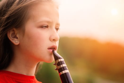 Young attractive girl playing clarinet in fall park