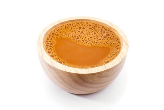 Hot milk tea in a wooden cup on white background