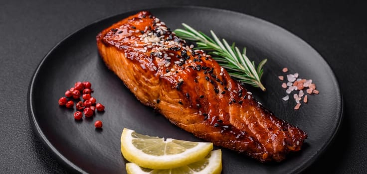 Delicious grilled red salmon fish with sauce, sesame seeds, spices and herbs on a dark concrete background
