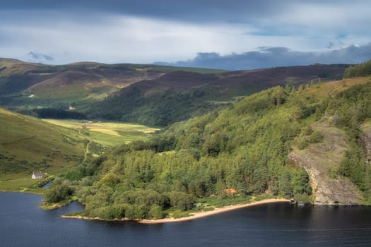 Beautiful aerial panorama with houses, lake, sandy beach, green forest and mountains. Lough Dan in Wicklow Mountains, Ireland