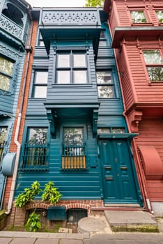 Facade of colorful wooden residential buildings painted in red and green, with wrought iron window, at an alley in Kuzguncuk neighborhood, Uskudar district, Istanbul, Turkey