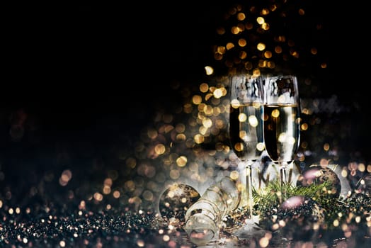Two champagne glasses and christmas decoration over dark golden bokeh background. New year and christmas luxury party celebration. Sparkling new year 2020 backdrop layout design.