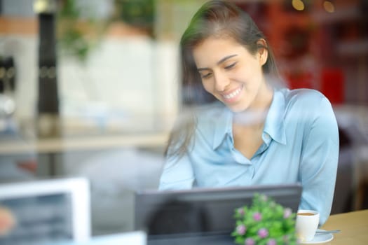 Happy elegant woman using tablet in a bar interior