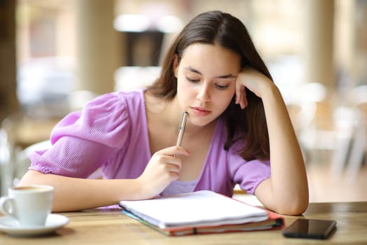 Student memorizing notes sitting in a restaurant terrace