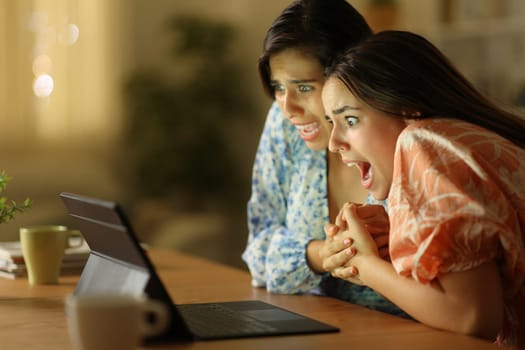 Terrified women watching media on laptop in the night at home