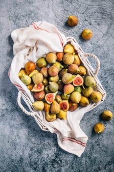 Freshly picked organic green figs in a basket on grey background