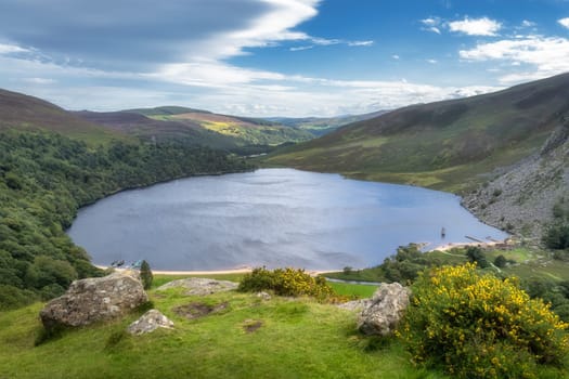 View on Lough Tay, called Guiness Lake with moored Viking longships and wooden village in Wicklow Mountains, Ireland