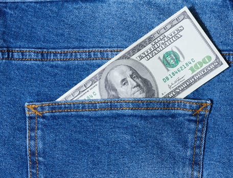 Paper American dollar bills protrude from the back pocket of blue jeans