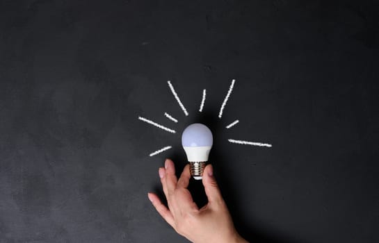 A woman's hand holds an electric lamp, the concept of searching for new ideas, startup