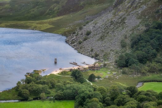 Viking longships moored on a wooden dock and village at the Lough Tay, called Guiness Lake in Wicklow Mountains, Ireland