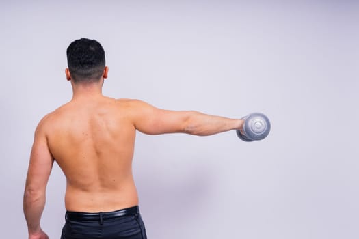 Athletic man doing exercises with dumbbell at biceps on a white background. Strength and motivation