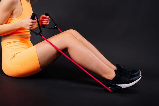 Fitness woman doing jumping exercises with a skipping rope on colorful yellow background.