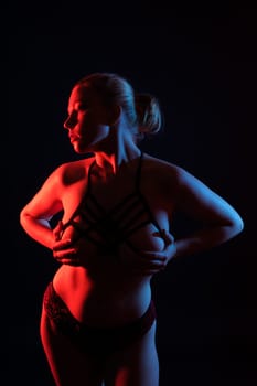 Beautiful female body. Isolated on a dark studio background. Plump woman covering breast.
