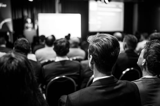 Speaker giving a talk in conference hall at business event. Rear view of unrecognizable people in audience at the conference hall. Business and entrepreneurship concept