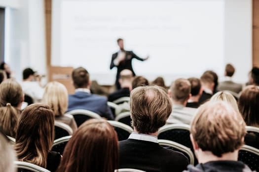 Speaker giving a talk in conference hall at business event. Rear view of unrecognizable people in audience at the conference hall. Business and entrepreneurship concept