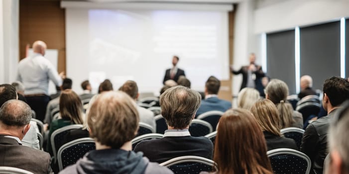 I have a question. Group of business people sitting at the chairs in conference hall. Businessman standing up asking a question. Conference and Presentation. Business and Entrepreneurship.