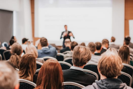 Speaker giving a talk in conference hall at business event. Rear view of unrecognizable people in audience at the conference hall. Business and entrepreneurship concept