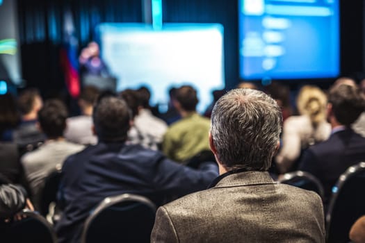Speaker giving a talk in conference hall at business event. Rear view of unrecognizable people in audience at the conference hall. Business and entrepreneurship concept