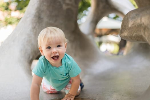 Child playing on outdoor playground. Toddler plays on school or kindergarten yard. Active kid on stone sculpured slide. Healthy summer activity for children. Little boy climbing outdoors