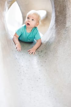 Child playing on outdoor playground. Toddler plays on school or kindergarten yard. Active kid on stone sculpured slide. Healthy summer activity for children. Little boy climbing outdoors