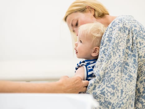 child beeing vaccinated by pediatrician in presence of his mother. Preventive vaccination against Diphtheria, whooping cough, tetanus, hepatitis, haemophilus influenzae, pneumococcus, poliomyelitis.