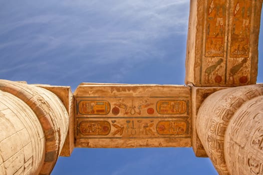 Columns with color hieroglyphs in Karnak temple. Blue sky in the background.. Luxor, Egypt. Horizontally