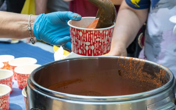 Tomato soup with pasta is a Polish dish. Zupa pomidorowa. Hot soup made from grated tomatoes. People and tourists walk, eat and buy food at the street food festival. Ukraine, Kyiv - August 17, 2023