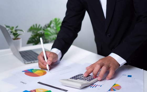 Business development ideas for success and growth. Businessman taps pen on document with calculator for planning future growth of his organization. Finance, management, plans, management, strategy
