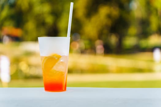 A glass with a refreshing summer cocktail on a blurred natural green background.