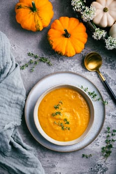 Pumpkin soup with pumpkin seeds served in bowl on rustic kitchen table