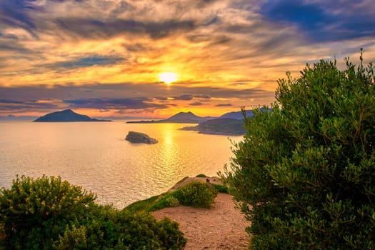 Beautiful sunset on Mediterranean sea coast, summer evening at ancient Temple of Poseidon, Sounio, Greece. Tranquil coastal landscape with clear blue waters.