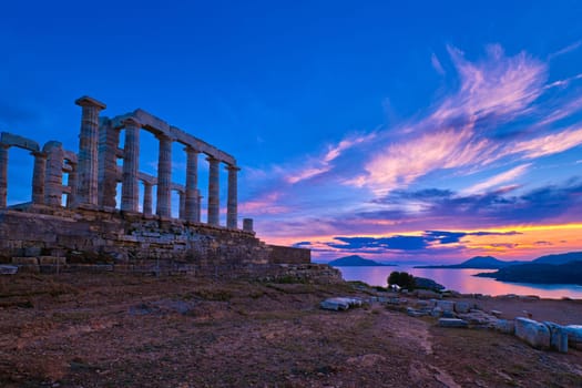 Beautiful sunset sky and ancient ruins of temple of Poseidon, cape Sounio, Aegean sea coast, Greece. Travel destination of Athens area, important center of ancient Greek religion for Olympian Greek mythology, god of the sea and earthquakes,