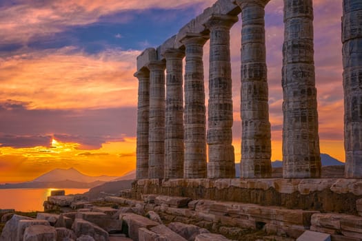 Beautiful sunset sky and ancient ruins of temple of Poseidon, cape Sounio, Aegean sea coast, Greece. Travel destination of Athens area, important center of ancient Greek religion for Olympian Greek mythology, god of the sea and earthquakes,