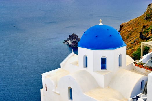 Beautiful view of Santorini island village or town, Greece. Whitewashed houses and churches, blue dome, sea waters of caldera bay, rough cliffs. Famous tourist attraction, romantic travel destination, summer vacations.