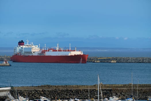 LNG or liquified natural gas carrier moored by industrial pier on hazy evening. Alternative gas supply, commercial freight, energy crisis, regasification, diversification, fuel and energy generation.