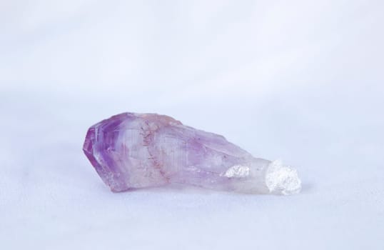 Brazilian amethyst fragment. Isolated over white fabric cloth