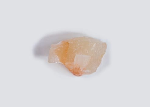 Amber calcite fragment, believed to have beneficial health properties. Isolated over white fabric cloth