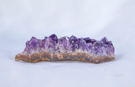 Amethyst geode piece. Isolated over white fabric cloth
