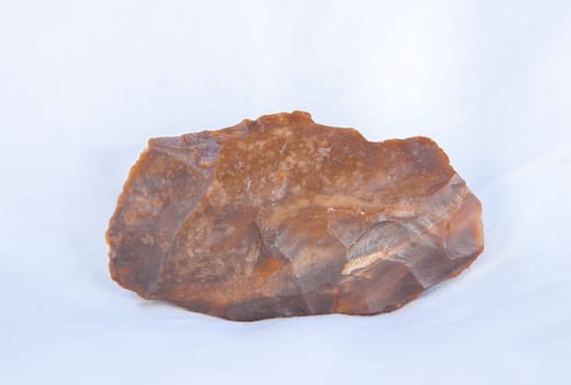 Silex fragment in pure form, raw material used for lithic industry at prehistoric times. Isolated over white fabric cloth