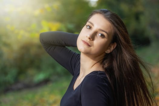 Portrait of beautiful young brunette woman posing outdoors in autumn. Horizontally.